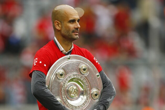 Bayern's head coach Pep Guardiola holds the Bundesliga title trophy after the German first division Bundesliga soccer match between FC Bayern Munich and FSV Mainz 05 at the Allianz Arena in Munich, Germany, Saturday, May 23, 2015. (AP Photo/Matthias Schrader)
