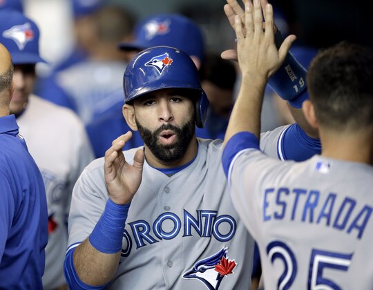 Toronto Blue Jays' Jose Bautista is congratulated by teammate Marco Estrada (25) after scoring on a Russell Martin two-run triple against the Houston Astros in the first inning of a baseball game Saturday, May 16, 2015, in Houston. (AP Photo/Pat Sullivan)