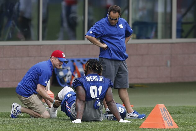 New York Giants defensive end Robert Ayers Jr., center, is checked by trainers during an NFL football organized team activity, Wednesday, May 27, 2015, in East Rutherford, N.J. (AP Photo/Julio Cortez)