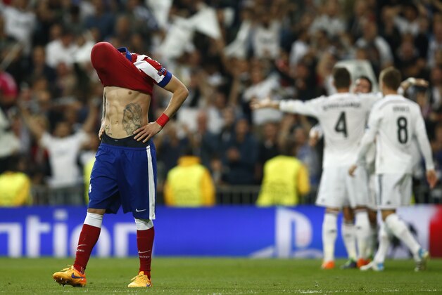Atletico's Gimenez reacts as Real Madrid players celebrate in the background at the end of the second leg quarterfinal Champions League soccer match between Real Madrid and Atletico Madrid at Santiago Bernabeu stadium in Madrid, Spain, Wednesday, April 22, 2015. Real Madrid defeated Atletico 1-0. (AP Photo/Andres Kudacki)