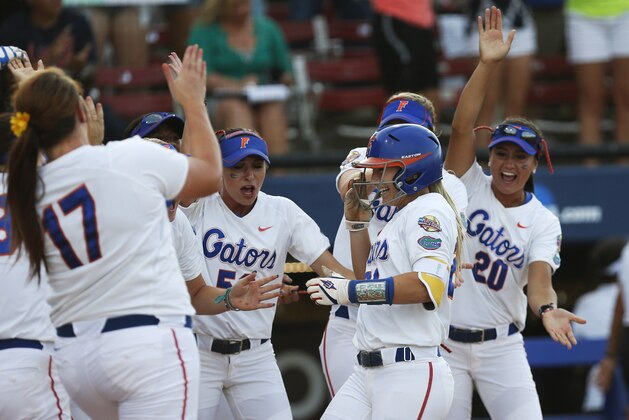 Florida's Kirsti Merritt, center, is greeted by her teammates at home plate following her home run in the second inning of an NCAA Women's College World Series softball tournament game against Alabama in Oklahoma City, Tuesday, June 3, 2014. (AP Photo/Sue Ogrocki)