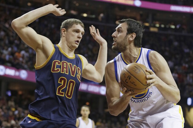 Golden State Warriors’ Andrew Bogut (12), from Australia, tries to get past Cleveland Cavaliers Timofey Mozgov (20) during an NBA basketball game Thursday, Feb. 26, 2015, in Cleveland. (AP Photo/Tony Dejak)