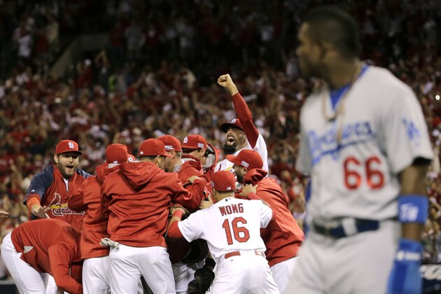 10ThingstoSeeSports - St. Louis Cardinals players celebrate after their 3-2 win over Los Angeles Dodgers in Game 4 of baseball's NL Division Series, Tuesday, Oct. 7, 2014, in St. Louis as Los Angeles Dodgers right fielder Yasiel Puig, right, looks on. (AP Photo/Charles Rex Arbogast, File)