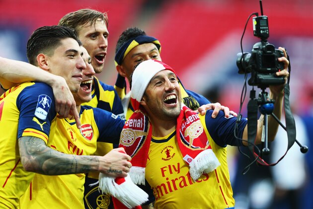 LONDON, ENGLAND - MAY 30:  (L-R) Hector Bellerin, Laurent Koscielny, Nacho Monreal, Alex Oxlade-Chamberlain and Santi Cazorla use a photographers camera as they celebrate victory after the FA Cup Final between Aston Villa and Arsenal at Wembley Stadium on May 30, 2015 in London, England. Arsenal beat Aston Villa 4-0.  (Photo by Paul Gilham/Getty Images)