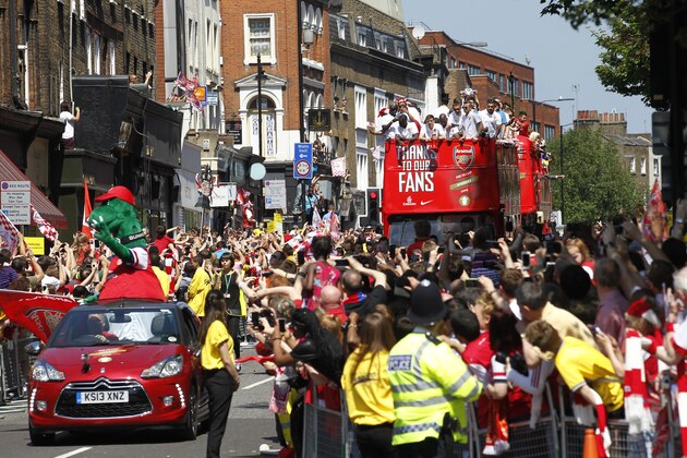 Arsenal's soccer team players parade through the street of London Sunday, May 18, 2014, aboard an open top bus in celebration of their English FA Cup win. Aaron Ramsey scored in extra time to clinch a 3-2 victory over Hull on Saturday, making Arsenal FA Cup Winners for the fifth time in Arsene Wenger's 14-year  tenure as coach of The Gunners.(AP Photo/Sang Tan)