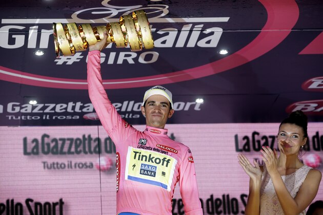 Spain's Alberto Contador holds up the trophy as former Miss Italy Cristina Chiabotto applauds, after winning the Giro d'Italia, Tour of Italy cycling race, in Milan, Italy, Sunday, May 31, 2015. Alberto Contador clinched his second Giro d'Italia title on Sunday, remaining on course to become the first cyclist since 1998 to win the Italian classic and the Tour de France in the same year. (AP Photo/Antonio Calanni)