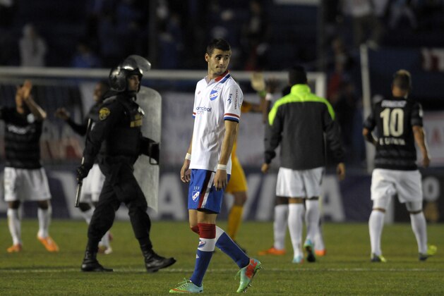 Gaston Pereiro of Uruguay's Nacional, center, walks from the pitch after loosing a Copa Libertadores soccer game against Colombia's Atletico Nacional in Montevideo, Uruguay, Tuesday, March 18, 2014. Atletico Nacional won the match 1-0. (AP Photo/Matilde Campodonico)