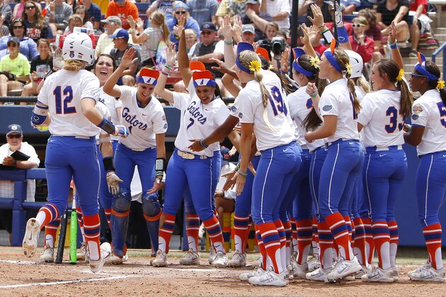 Florida's Taylor Fuller (12) is met by her team as she scores in the fourth inning during an NCAA Women's College World Series softball game against Auburn in Oklahoma City, Sunday, May 31, 2015. (AP Photo/Alonzo Adams)