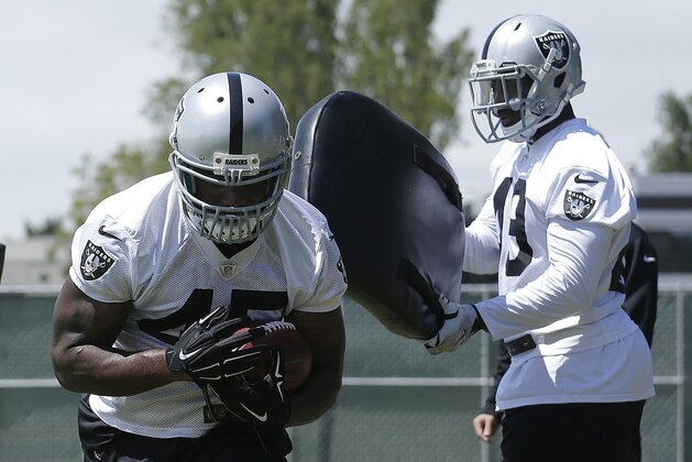 Oakland Raiders fullback Marcel Reece, left, runs through pads during practice at an NFL football facility in Alameda, Calif., Tuesday, June 2, 2015. (AP Photo/Jeff Chiu)