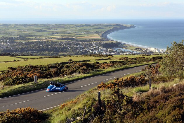 RAMSEY, ISLE OF MAN - JUNE 05:  The town of Ramsey catches the evening light in the distance as a competitor rides during a practice session on June 5, 2009, Isle Of Man, United Kingdom. Adverse weather conditions prevented the much anticipated Superbike race from taking place on Saturday and, depending on the rain, may be off all weekend. The annual TT race is one of the highlights of the motorbike racing calender with fans travelling from around the globe to watch riders compete in the 37 and three quarter mile lap exceeding speeds of 200mph.  (Photo by Dan Kitwood/Getty Images)