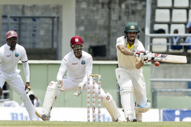 Australia's Mitchell Johnson, right, bats as West Indies wicket keeper, captain Denesh Ramdin, center, and Darren Bravo, left, looks on, during the second day of their first cricket Test match in Roseau, Dominica, Thursday, June 4, 2015. (AP Photo/Arnulfo Franco)