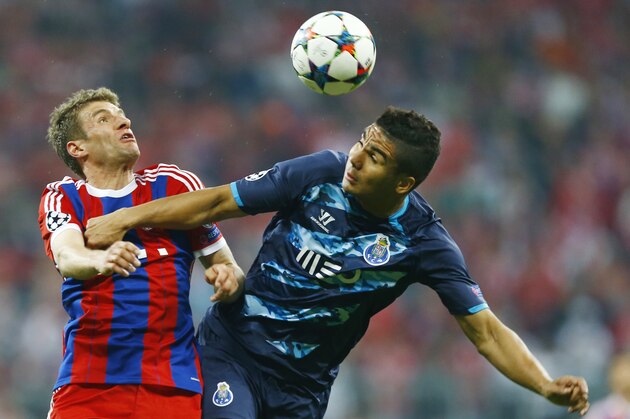 Bayern's Thomas Mueller, left, and Porto's Carlos Casemiro challenge for the ball during the soccer Champions League quarterfinal second leg match between Bayern Munich and FC Porto at the Allianz Arena in Munich, southern Germany, Tuesday, April 21, 2015. (AP Photo/Matthias Schrader)