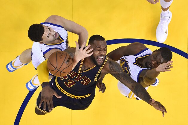 Cleveland Cavaliers forward LeBron James, center, loses the ball between Golden State Warriors guard Klay Thompson, left, and forward Harrison Barnes during the first half of Game 1 of basketball's NBA Finals in Oakland, Calif., Thursday, June 4, 2015. The Warriors won 108-100 in overtime. (John G. Mabanglo/EPA Pool via AP)