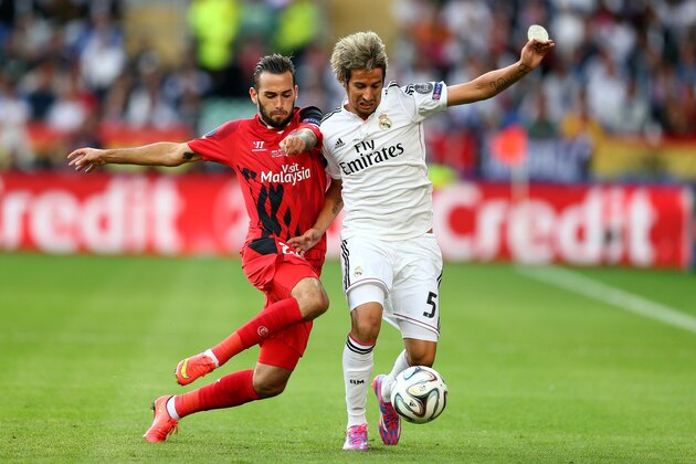 CARDIFF, WALES - AUGUST 12:  Aleix Vidal of Sevilla and Fabio Coentrao of Real Madrid compete for the ball during the UEFA Super Cup between Real Madrid and Sevilla FC at Cardiff City Stadium on August 12, 2014 in Cardiff, Wales.  (Photo by Clive Mason/Getty Images)