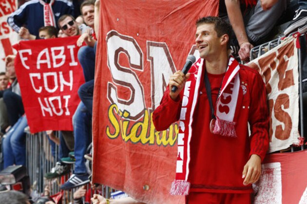 Bayern's Thomas Mueller, right, celebrates with fans as the team celebrate winning the Bundesliga title after the German first division Bundesliga soccer match between FC Bayern Munich and FSV Mainz 05 at the Allianz Arena in Munich, Germany, Saturday, May 23, 2015. (AP Photo/Matthias Schrader)