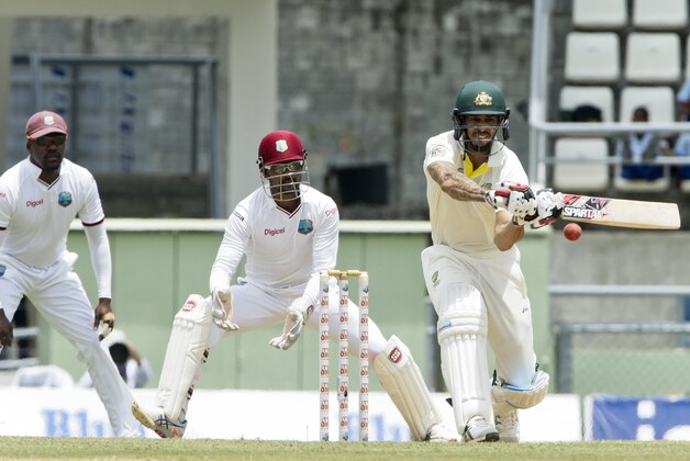 Australia's Mitchell Johnson, right, bats as West Indies wicket keeper, captain Denesh Ramdin, center, and Darren Bravo, left, looks on, during the second day of their first cricket Test match in Roseau, Dominica, Thursday, June 4, 2015. (AP Photo/Arnulfo Franco)