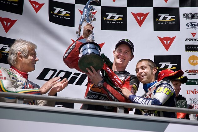 Italy’s Valentino Rossi, right,  presents Britain's John McGuinness with the Trophy for winning the Isle of Man TT Superbike Race, on Monday June 8 2009. John McGuinness established himself as the second most successful Isle of Man Tourist Trophy rider of all time with victory in the Dainese Superbike race. The TT veteran was neck and neck with Mike Hailwood on 14 wins going into the opening race on the Isle of Man but a flawless ride saw the HM Plant Honda move to 15 and second outright. McGuinness' team-mate Steve Plater, winner of last year's Supersport race, claimed second - 18.55 seconds behind McGuinness with Hydrex Honda rider Guy Martin in third. (AP Photo/Pete Williamson)