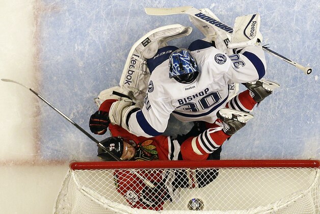 Chicago Blackhawks' Jonathan Toews, bottom, falls into the net past Tampa Bay Lightning goalie Ben Bishop during the first period in Game 3 of the NHL hockey Stanley Cup Final on Monday, June 8, 2015, in Chicago. (AP Photo/Nam Y. Huh)