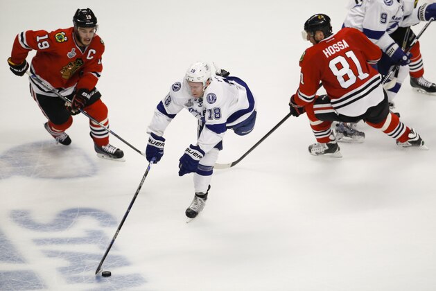 Tampa Bay Lightning's Ondrej Palat, center, of the Czech Republic, chases after a loose puck between Chicago Blackhawks' Jonathan Toews, left, and Marian Hossa, of Slovakia, during the third period in Game 4 of the NHL hockey Stanley Cup Final Wednesday, June 10, 2015, in Chicago. (AP Photo/Charles Rex Arbogast)