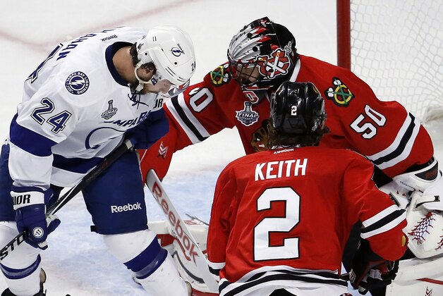 Chicago Blackhawks goalie Corey Crawford (50) keeps his eye on the puck along side teammate Duncan Keith (2) and Tampa Bay Lightning's Ryan Callahan (24) during the first period in Game 4 of the NHL hockey Stanley Cup Final Wednesday, June 10, 2015, in Chicago. (AP Photo/Charles Rex Arbogast)
