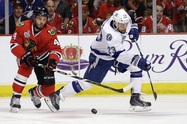 Tampa Bay Lightning's J.T. Brown, right, misses the puck along side Chicago Blackhawks' Niklas Hjalmarsson during the first period in Game 4 of the NHL hockey Stanley Cup Final Wednesday, June 10, 2015, in Chicago. (AP Photo/Nam Y. Huh)