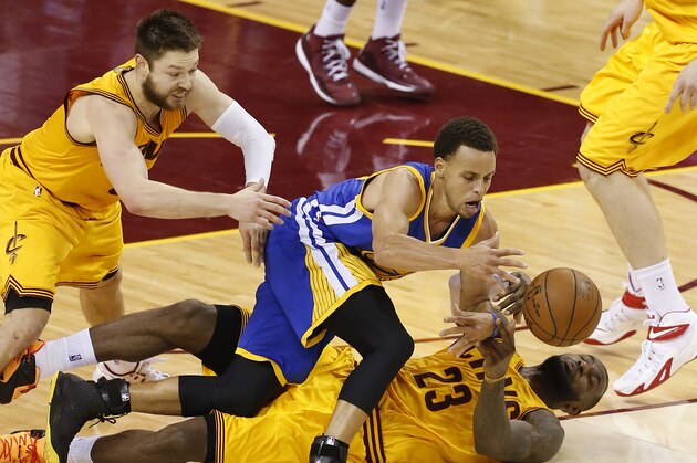 Golden State Warriors guard Stephen Curry and Cleveland Cavaliers forward LeBron James (23) and guard Matthew Dellavedova, left, go to the floor for a loose ball during the second half of Game 3 of basketball's NBA Finals in Cleveland, Tuesday, June 9, 2015. (AP Photo/Paul Sancya)