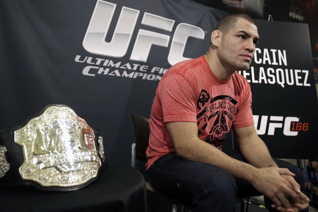 Sitting beside his championship belt, UFC heavyweight champion Cain Velasquez answers questions during a media availability Thursday, Oct. 17, 2013, in Houston. Velasquez will face former UFC heavyweight champion Junior Dos Santos in a rematch in Houston Saturday. He beat Santos in a five-round decision in December to regain the title after Santos won in a knockout in the first meeting in 2011. (AP Photo/Pat Sullivan)
