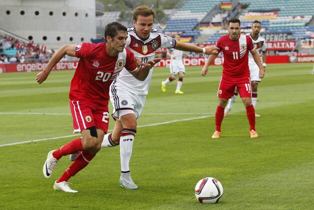 Gibraltar’s Jean Carlos Garcia, left and Germany’s Mario Gotze, center, fight for the ball during the Group D, Euro 2016 qualifying soccer match between Gibraltar and Germany at the Algarve stadium, outside Faro, southern Portugal, Saturday, June 13, 2015. (AP Photo/Francisco Seco)