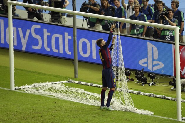 Barcelona's Gerard Pique removes the net from one goal as he celebrates after the Champions League final soccer match between Juventus Turin and FC Barcelona at the Olympic stadium in Berlin Saturday, June 6, 2015. Barcelona won the match 3-1. (AP Photo/Michael Sohn)