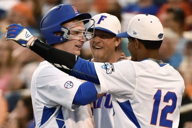 Florida's Peter Alonso, left, is greeted by Richie Martin (12), after scoring on a single by Mike Rivera during the fourth inning of an NCAA College World Series baseball game against Miami at TD Ameritrade Park in Omaha, Neb., Saturday, June 13, 2015. (AP Photo/Mike Theiler)