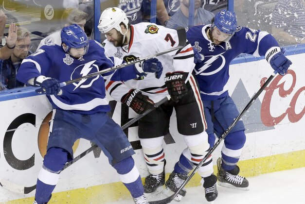 Chicago Blackhawks defenseman Brent Seabrook (7) gets sandwiched between Tampa Bay Lightning center Alex Killorn (17) and right wing Ryan Callahan (24) during the third period of Game 5 of the NHL hockey Stanley Cup Final, Saturday, June 13, 2015, in Tampa, Fla. The Blackhawks won 2-1. (AP Photo/John Raoux)