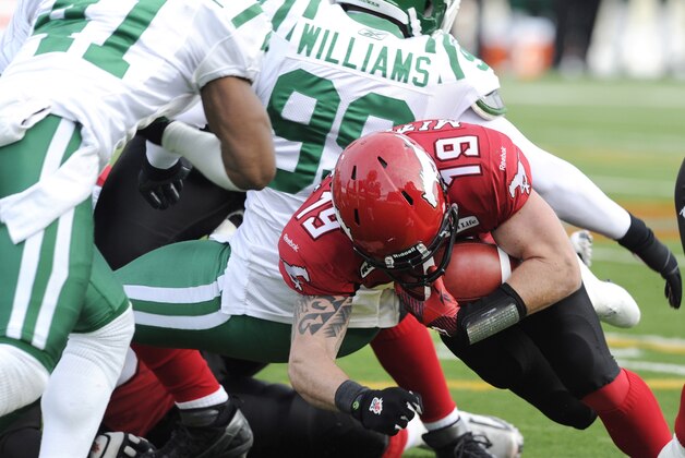 Calgary Stampeders' quarterback Bo Levi Mitchell, right, dives over the goal line for a touchdown passing Saskatchewan Roughriders' Tyron Brackenridge, left, and Shomari Williams during first half CFL Western semi-final football action in Calgary, Alberta on Sunday, Nov. 11, 2012. (AP Photo/Larry MacDougal, The Canadian Press)