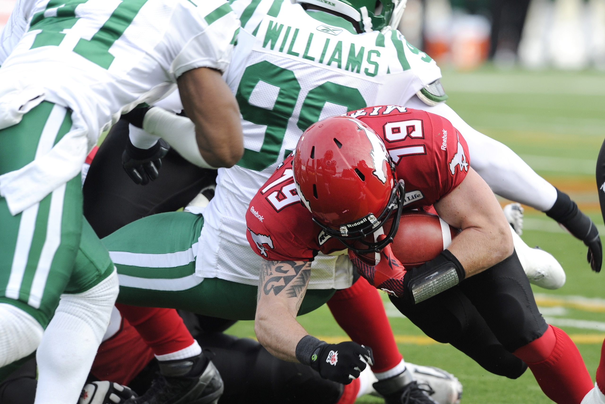 Calgary Stampeders' quarterback Bo Levi Mitchell, right, dives over the goal line for a touchdown passing Saskatchewan Roughriders' Tyron Brackenridge, left, and Shomari Williams during first half CFL Western semi-final football action in Calgary, Alberta on Sunday, Nov. 11, 2012. (AP Photo/Larry MacDougal, The Canadian Press)