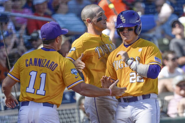 LSU's Kade Scivicque (22) is greeted at the dugout by hitting coach Andy Cannizaro (11) and Alex Bregman, center, after he scored on a sacrifice bunt by LSU infielder Danny Zardon in the seventh inning of an NCAA College World Series baseball elimination game against Cal State Fullertonat TD Ameritrade Park in Omaha, Neb., Tuesday, June 16, 2015. (AP Photo/Ted Kirk)