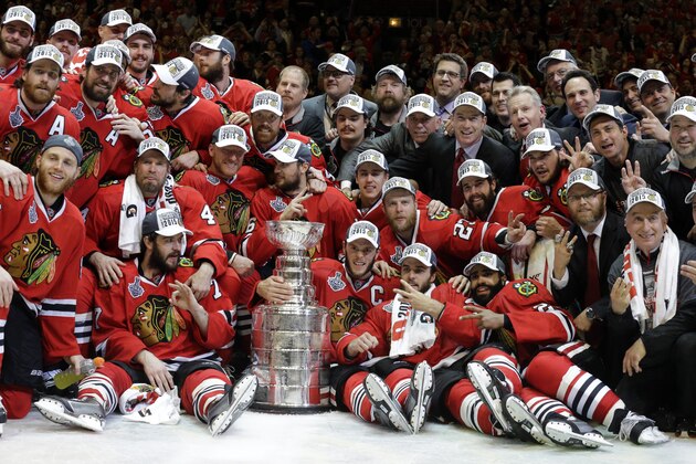 Members of the Chicago Blackhawks pose for pictures as they celebrate after defeating the Tampa Bay Lightning in Game 6 of the NHL hockey Stanley Cup Final series on Monday, June 15, 2015, in Chicago. The Blackhawks defeated the Lightning 2-0 to win the series 4-2. (AP Photo/Nam Y. Huh)