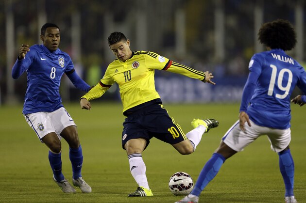 Colombia's James Rodriguez kicks the ball during a Copa America Group C soccer match against Brazil at the Monumental stadium in Santiago, Chile, Wednesday, June 17, 2015. At left Brazil's Elias, at right Brazil's Willian .(AP Photo/Jorge Saenz)