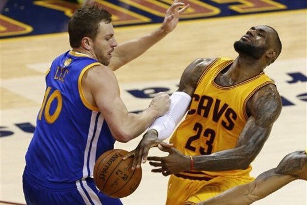Cleveland Cavaliers forward LeBron James (23) loose the ball as he's hilt by Golden State Warriors forward David Lee (10) during the second half of Game 4 of basketball's NBA Finals in Cleveland, Thursday, June 11, 2015. (AP Photo/Paul Sancya)