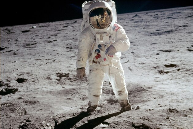 The reflections of Astronaut Neil Armstrong, the U.S. Flag, the Lunar Module and television camera, are reflected in the face mask of Astronaut Edwin