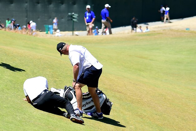 UNIVERSITY PLACE, WA - JUNE 19:  Jason Day of Australia is tended to by caddie Colin Swatton as he lays on the ninth green after falling due to dizziness during the second round of the 115th U.S. Open Championship at Chambers Bay on June 19, 2015 in University Place, Washington.  (Photo by Harry How/Getty Images)