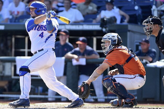 Florida Mike Rivera (4) follows through on an RBI-single that scored JJ Schwarz in front of Virginia catcher Matt Thaiss, second from left, in the sixth inning of an NCAA College World Series baseball game in Omaha, Neb., Friday, June 19, 2015. (AP Photo/Mike Theiler) Florida Mike Rivera (4) follows through on an RBI-single that scored JJ Schwarz in front of Virginia catcher Matt Thaiss, second from left, in the sixth inning of an NCAA College World Series baseball game in Omaha, Neb., Friday, June 19, 2015. (AP Photo/Mike Theiler)