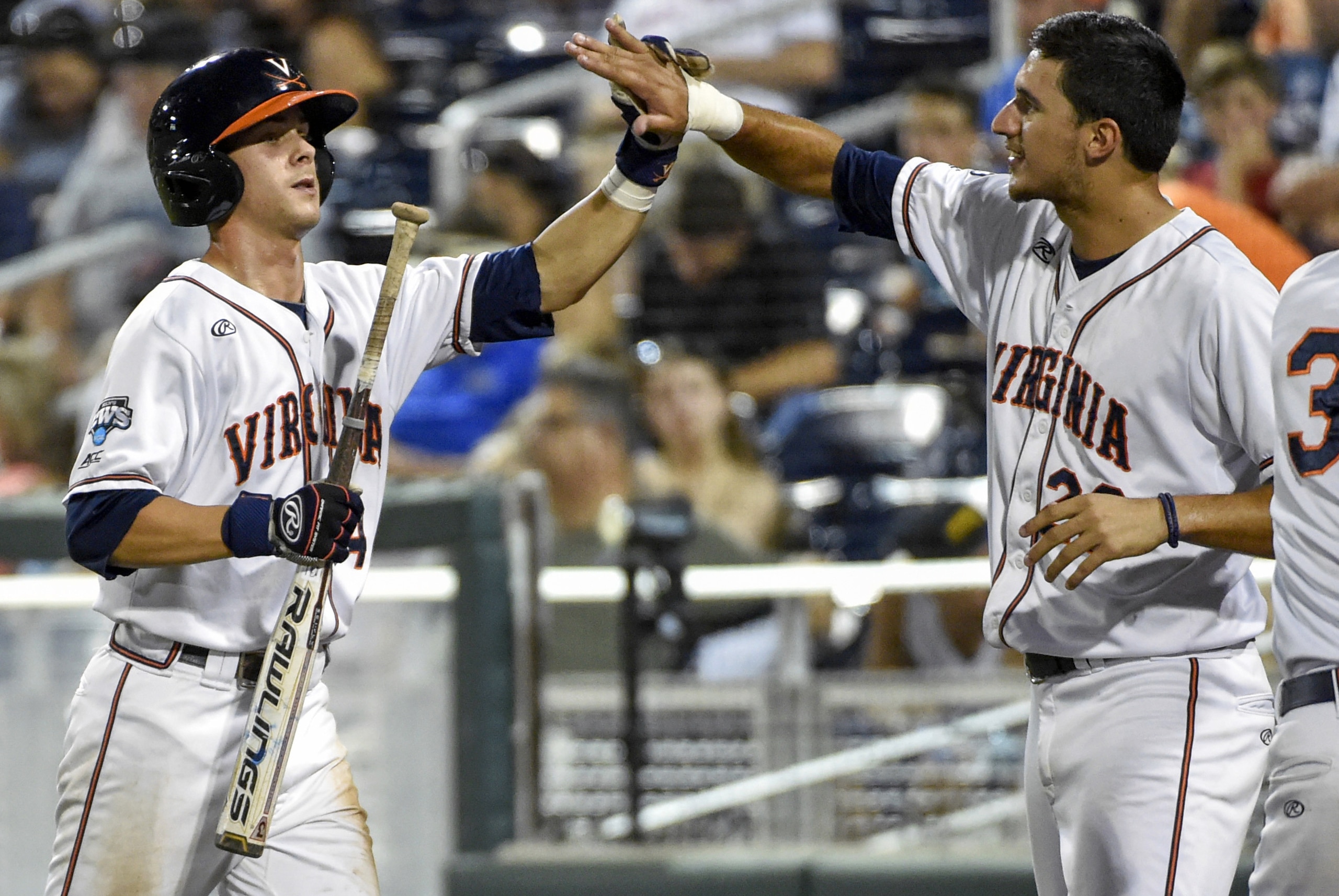 Virginia's Ernie Clement, left, celebrates with Daniel Pinero, right, after he scored on an RBI-sacrifice fly by Kenny Towns in the seventh inning of an NCAA College World Series baseball elimination game against Florida in Omaha, Neb., Saturday, June 20, 2015. (AP Photo/Mike Theiler)