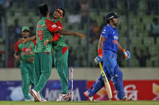 Bangladesh’s Mustafizur Rahman, left,  celebrates with teammate Nasir Hossain, center, the dismissal of India’s Suresh Raina, right, during the first one-day international cricket match between them in Dhaka, Bangladesh, Thursday, June 18, 2015. (AP Photo/ A.M. Ahad)