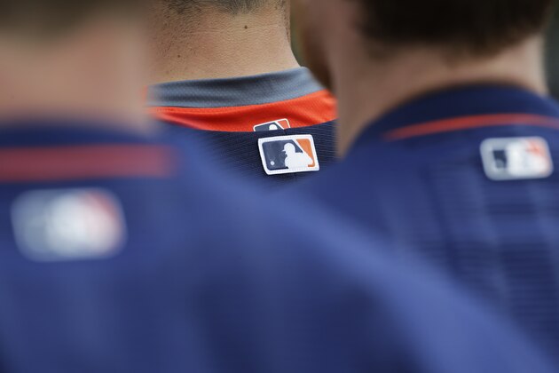The Major League Baseball logo is is seen on the back of Houston Astros jerseys as players stand on the field during a spring training baseball workout, Thursday, Feb. 26, 2015, in Kissimmee, Fla. (AP Photo/David Goldman)