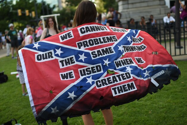 Mariangeles Borghini holds a burned Confederate flag during a rally to take down the Confederate flag at the South Carolina Statehouse, Saturday, June 20, 2015, in Columbia, S.C. Rep. Doug Brannon, R-Landrum, said it's past time for the Confederate flag to be removed from South Carolina's Statehouse grounds after nine people were killed at the Emanuel AME Church shooting. (AP Photo/Rainier Ehrhardt)