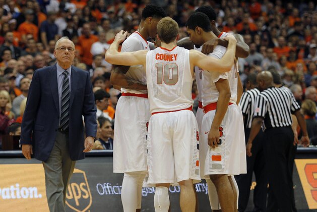 Syracuse head coach Jim Boeheim, left, walks near his players meeting on the court as referees discuss a scuffle that broke out after a flagrant foul one in the second half of an NCAA college basketball game against St. John's in Syracuse, N.Y., Saturday, Dec. 6, 2014. St. John’s won 69-57. (AP Photo/Nick Lisi)