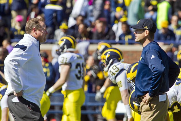 Michigan offensive coordinator Tim Drevno, left, talks with head coach Jim Harbaugh, right, as players warmup before the NCAA college football team's spring game in Ann Arbor, Mich., Saturday, April 4, 2015. (AP Photo/Tony Ding)