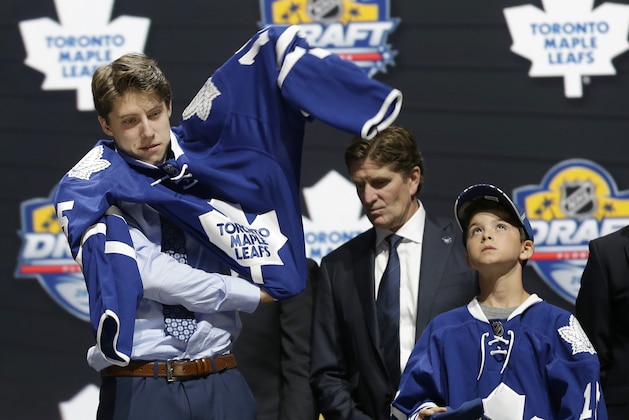 Mitch Marner puts on a Toronto Maple Leafs sweater after being chosen fourth overall during the first round of the NHL hockey draft, Friday, June 26, 2015, in Sunrise, Fla. (AP Photo/Alan Diaz)