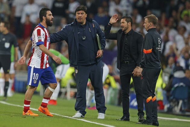 Atletico's Arda Turan, leaves the pitch after receiving a red card while Atletico's coach Diego Simeone, second right, gestures during the second leg quarterfinal Champions League soccer match between Real Madrid and Atletico Madrid at Santiago Bernabeu stadium in Madrid, Spain, Wednesday April 22, 2015. (AP Photo/Paul White)