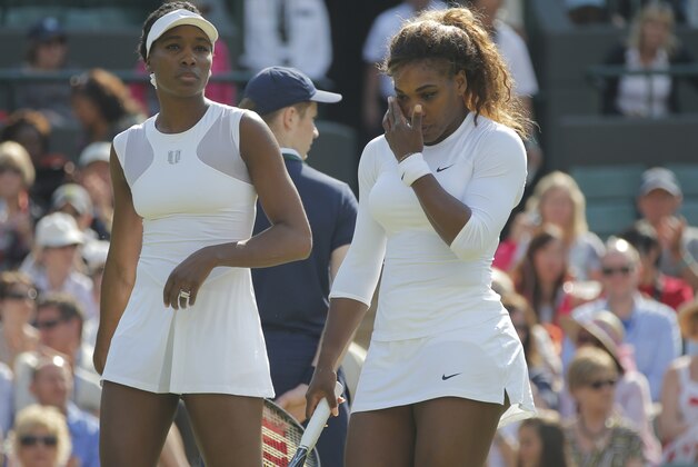 Serena Williams and Venus Williams, left, of the U.S prepare to play a point in their women's doubles match against Kristina Barrios of Germany and Stefanie Voegele of Switzerland at the All England Lawn Tennis Championships in Wimbledon, London, Tuesday July 1, 2014. The Williams sisters retired after 3 games. (AP Photo/Pavel Golovkin)