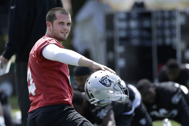 Oakland Raiders quarterback Derek Carr picks up his helmet while stretching during NFL football practice, Tuesday, June 2, 2015,  in Alameda, Calif. (AP Photo/Jeff Chiu)
